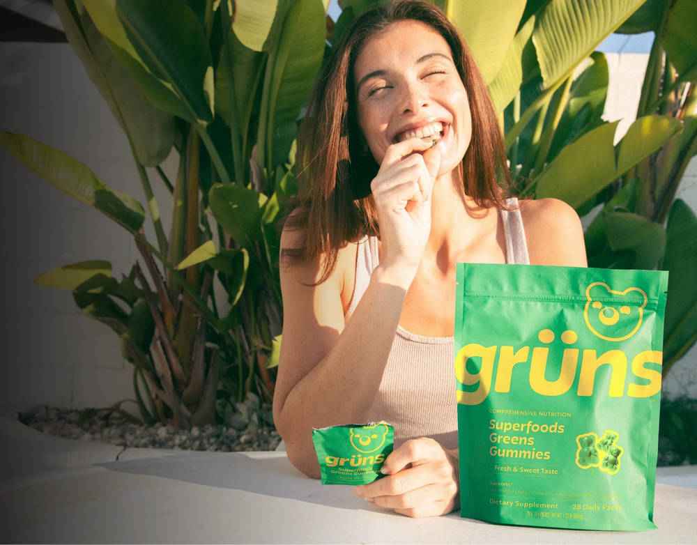 Woman eating Gr&uuml;ns gummy with product pouch