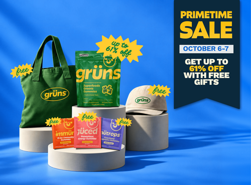 Grüns Superfoods Greens Gummies in a 28-pack green pouch on gray pedestals, surrounded by free gifts: a green Grüns tote bag, a beige Grüns cap, and single-serve packets of Immüne, Jüced, and Nütrops gummies. A "Primetime Sale" banner reads "October 6-7, get up to 61% off with free gifts."