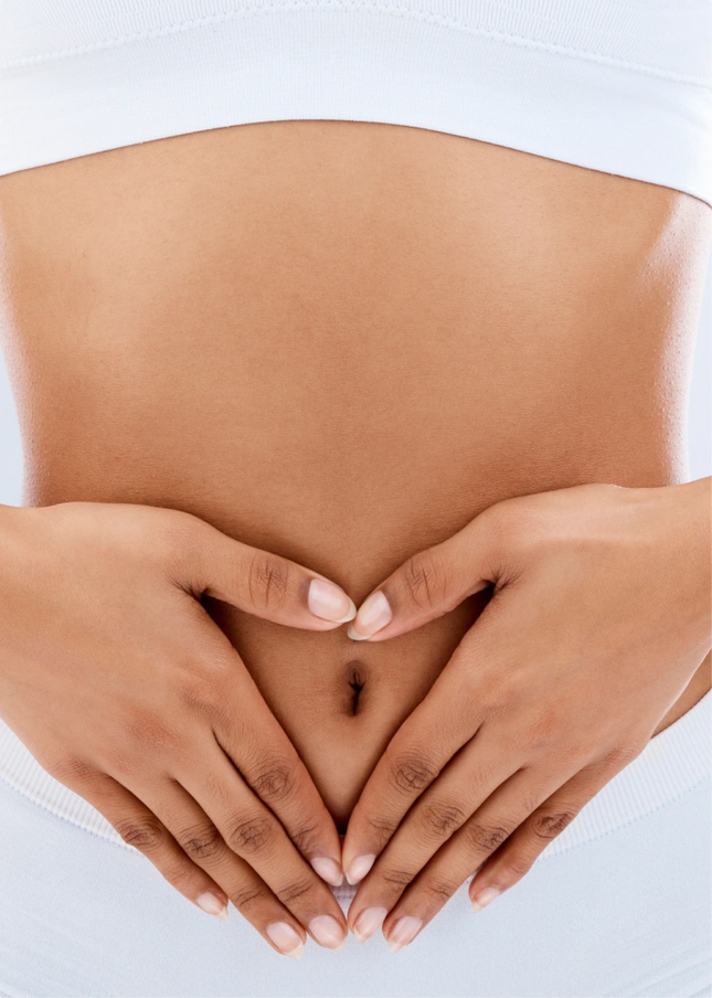 Hands forming a heart shape on a bare stomach.