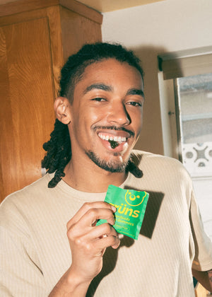 Man holding a green packet with of Grüns in a kitchen setting