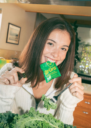 Woman holding a package of Grüns and kale in a kitchen