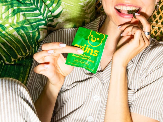 Woman holding Grüns sachet and about to eat a Grüns gummy