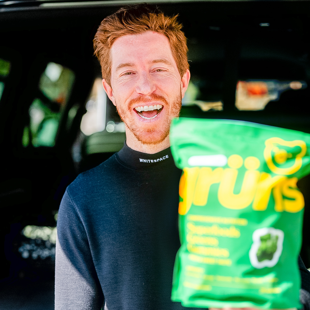 Person smiling, holding a green bag with yellow text.