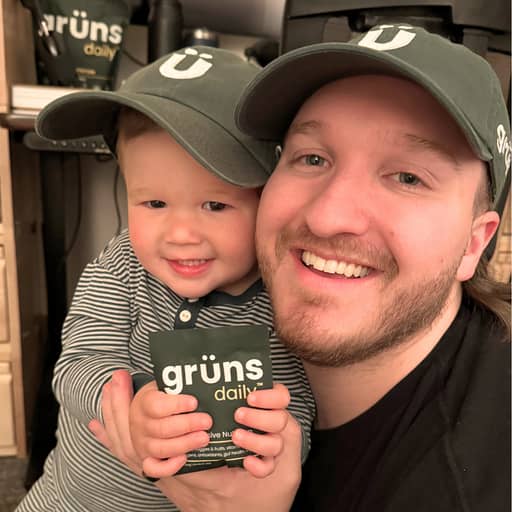 A smiling man and a child wearing matching green hats hold grüns daily packages.