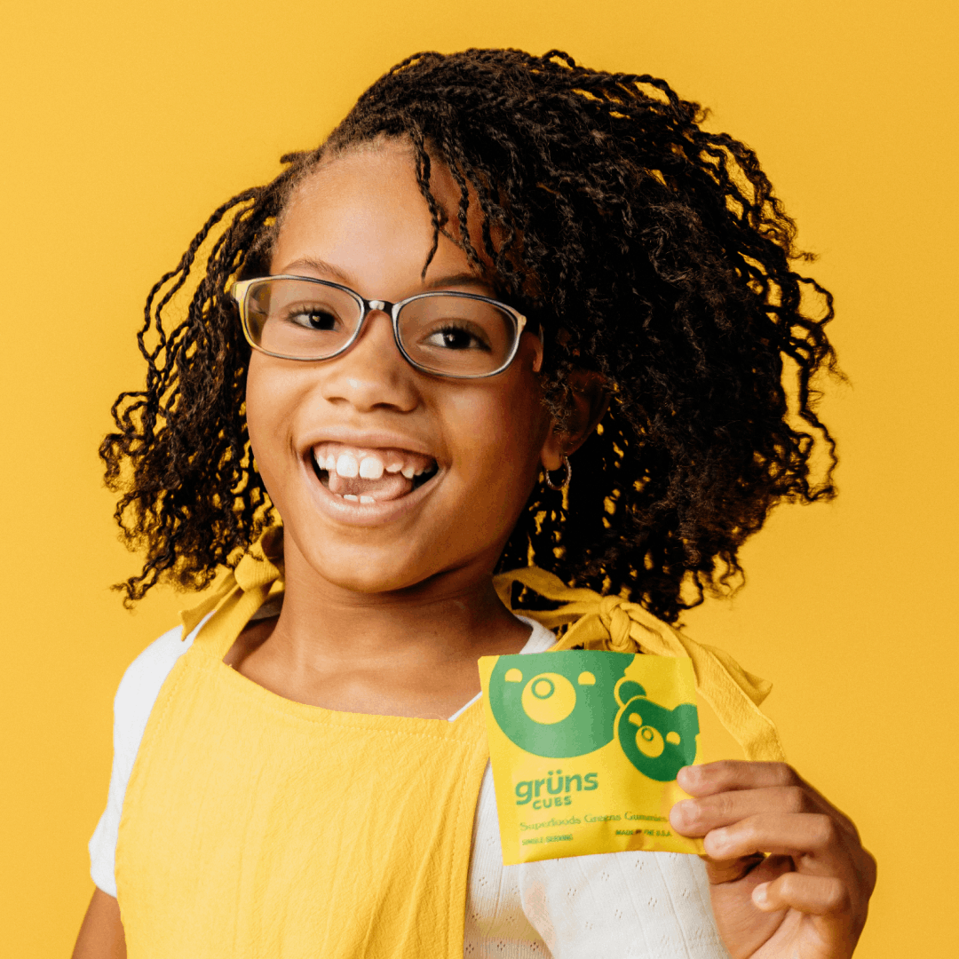 Smiling girl with curly hair holding a green and yellow packet.