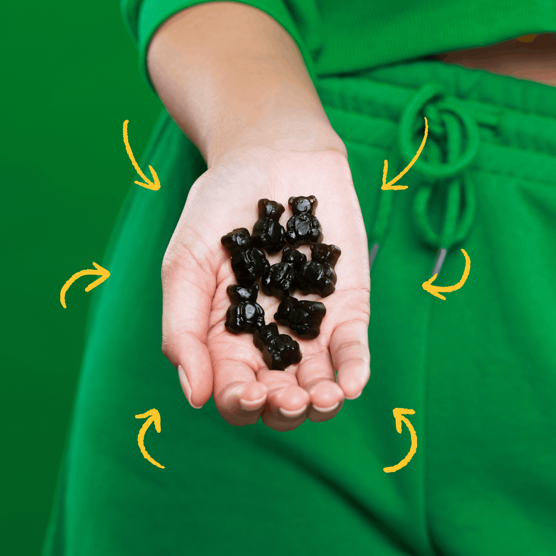 Hand holding black gummy bears against a green background.