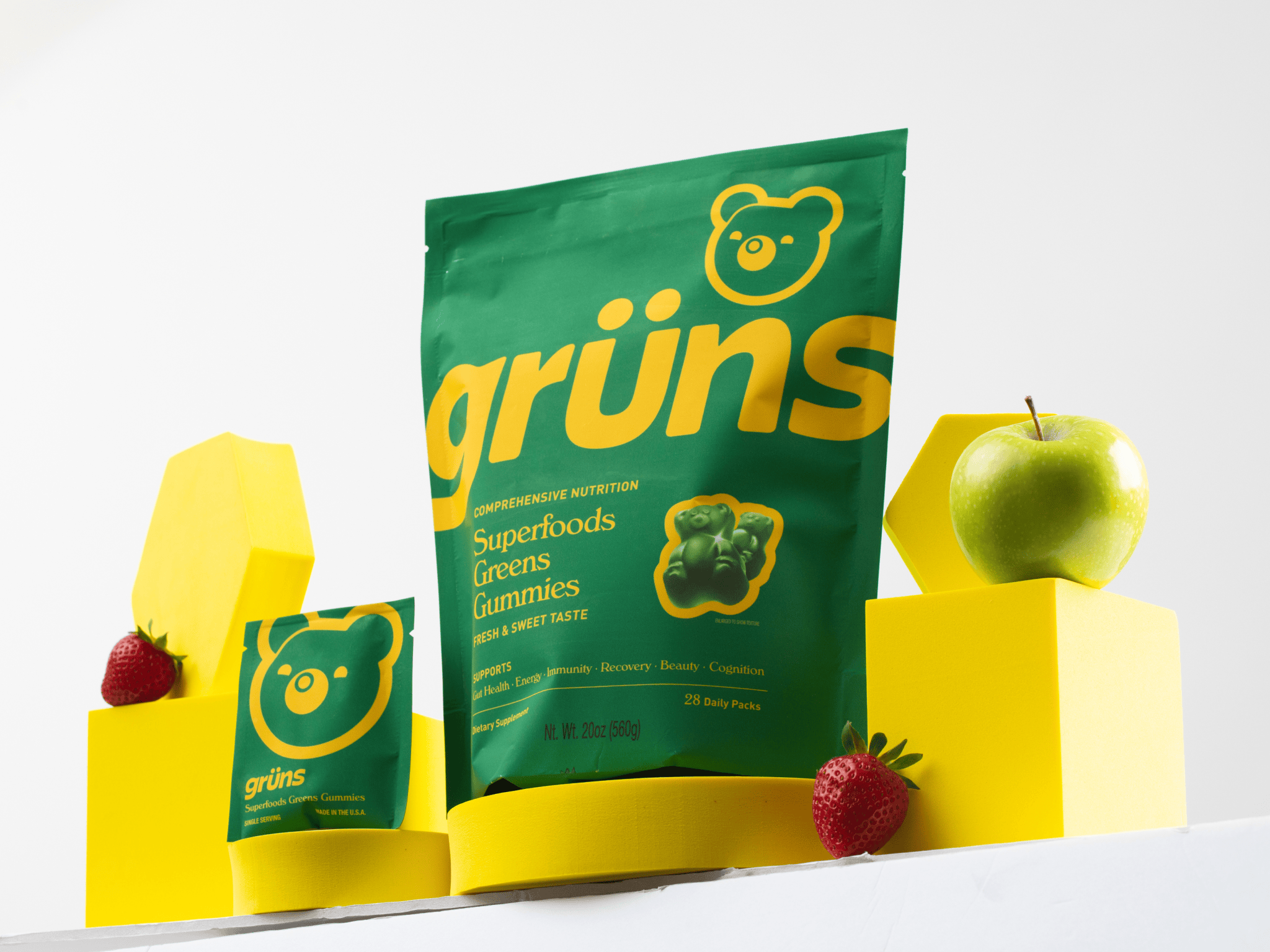 Green and yellow packaging of superfood gummies with an apple and strawberries.