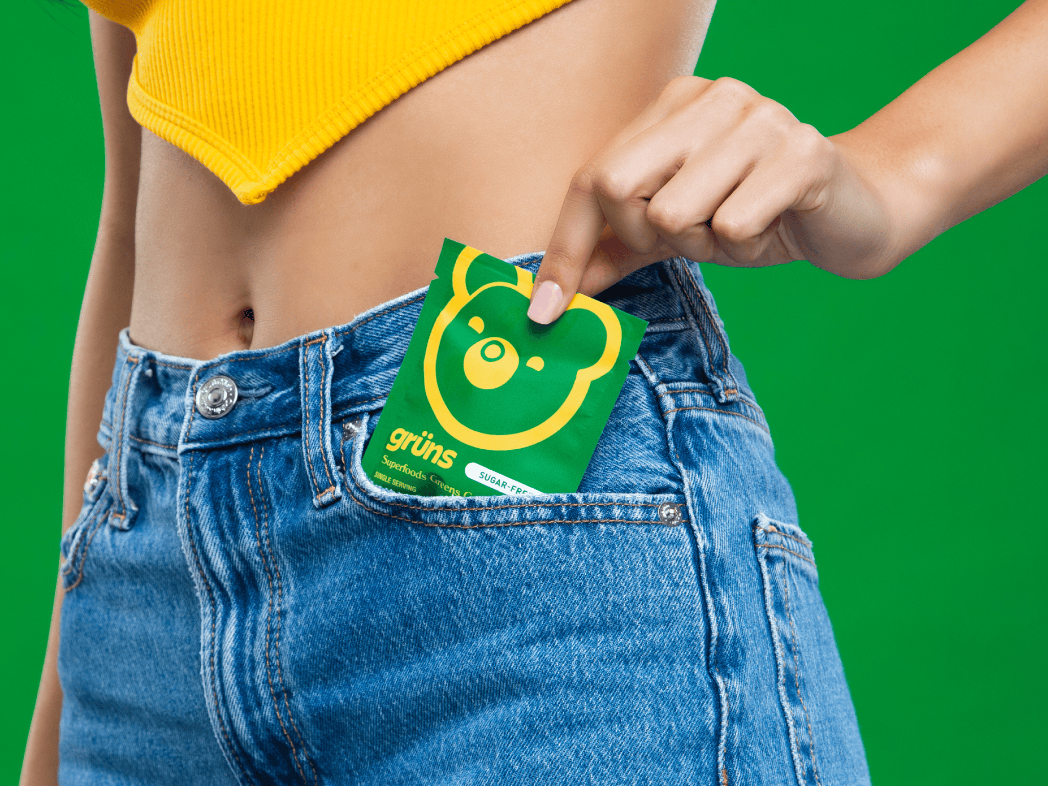 Person placing green package with bear design into jeans pocket.