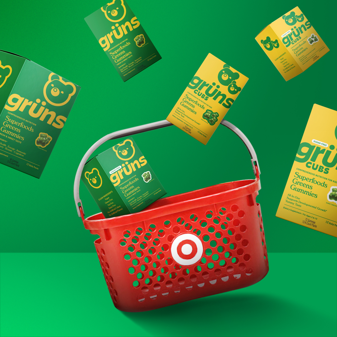 Boxes of Grüns Superfoods Gummies with a red shopping basket on a green background.