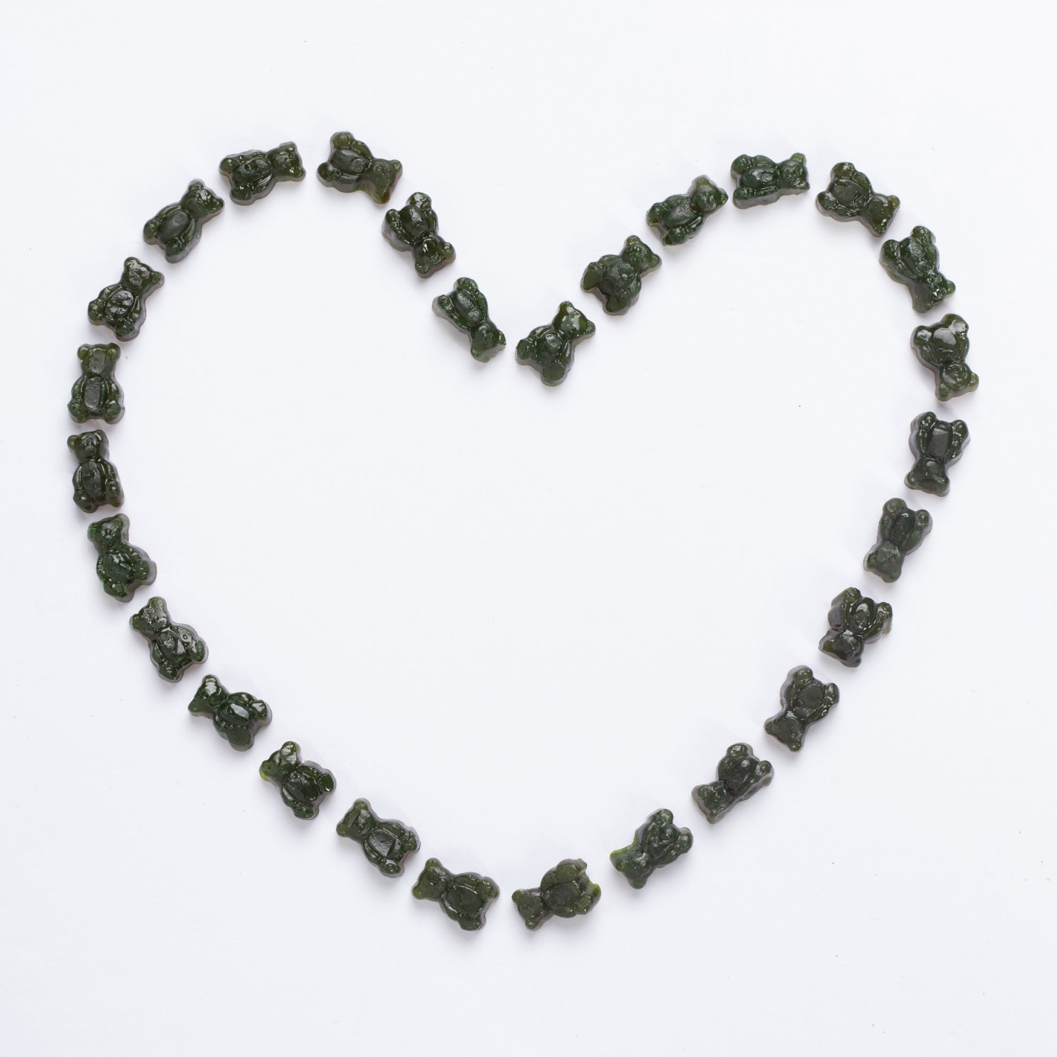 Gummy bears arranged in a heart shape on a white background.